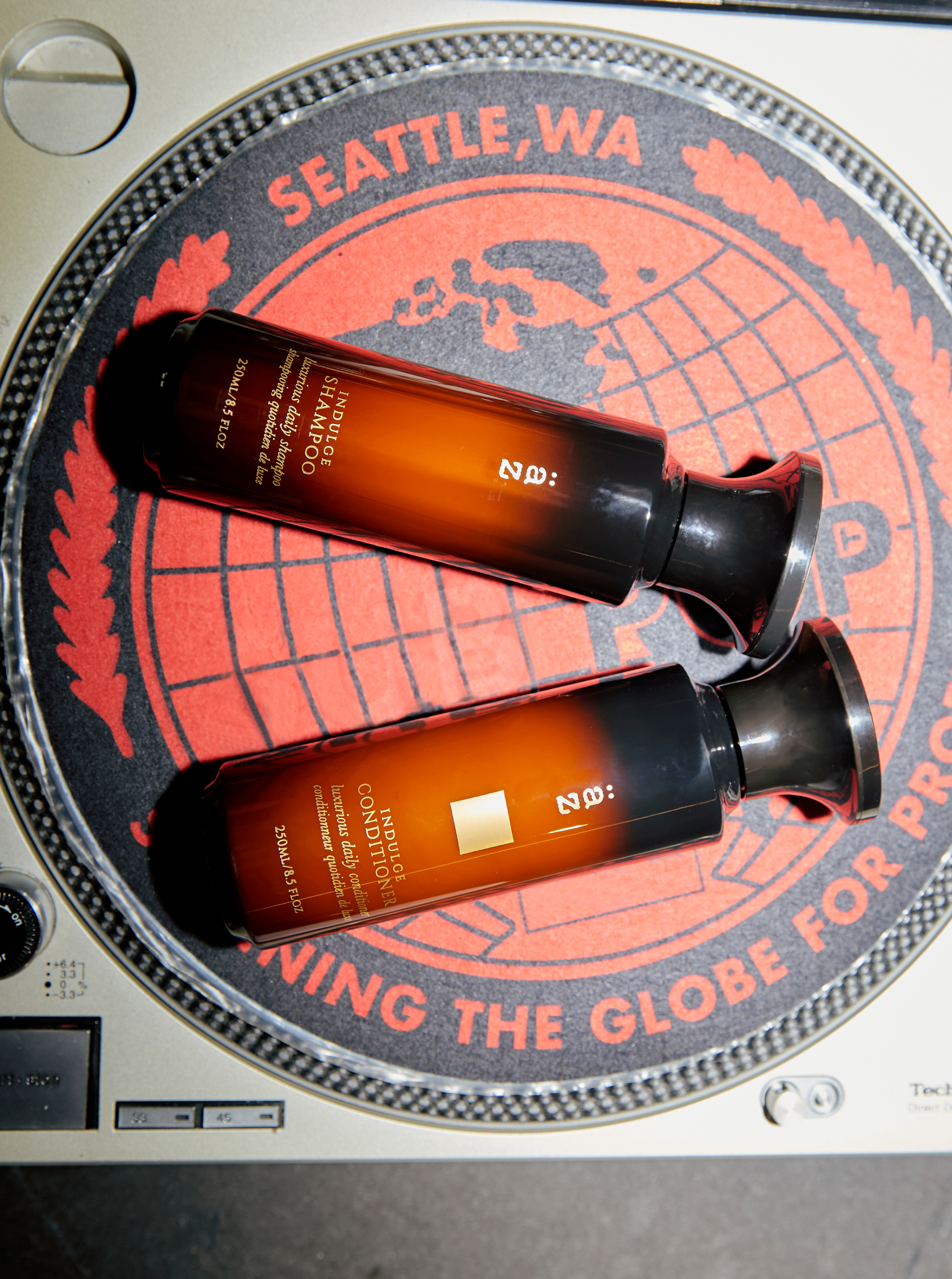 AZ Indulge Shampoo and Conditioner resting on a turntable platter with a red SEATTLE, WA slipmat