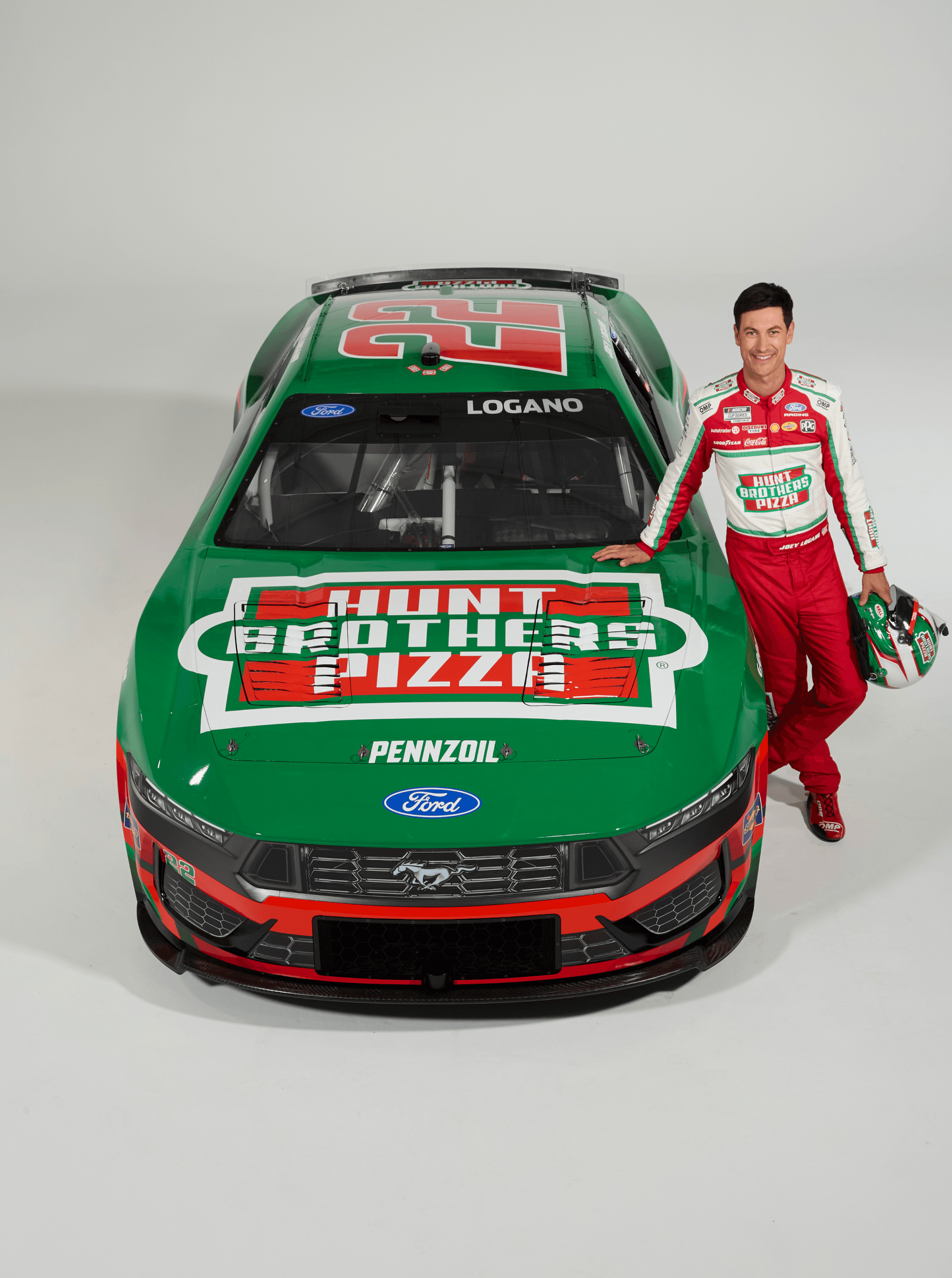 Green number 22 Ford stock car with Hunt Brothers Pizza hood graphics, driver standing at the fender with his helmet