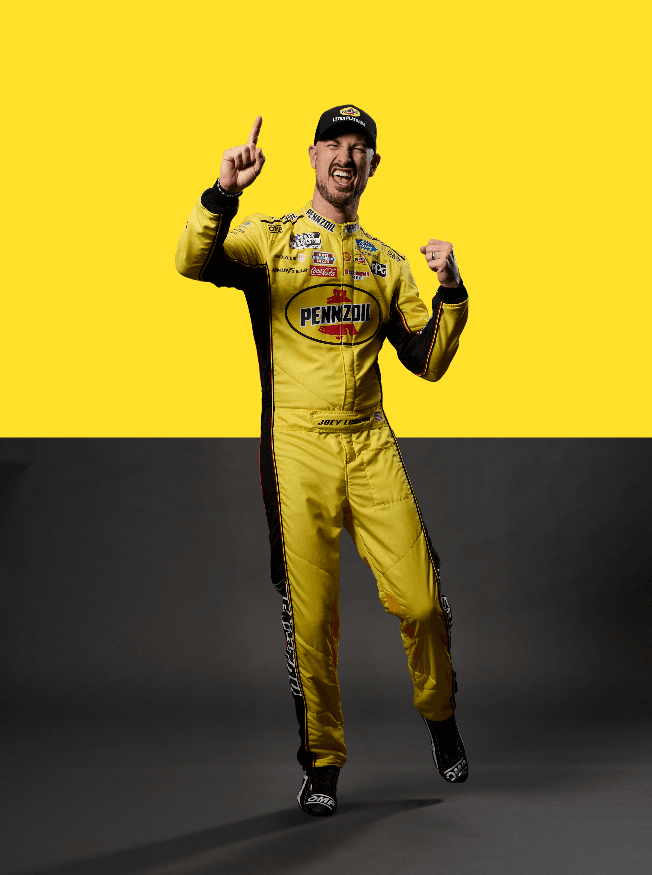 Driver in a Pennzoil suit and cap celebrating with one finger raised against a split yellow and grey backdrop