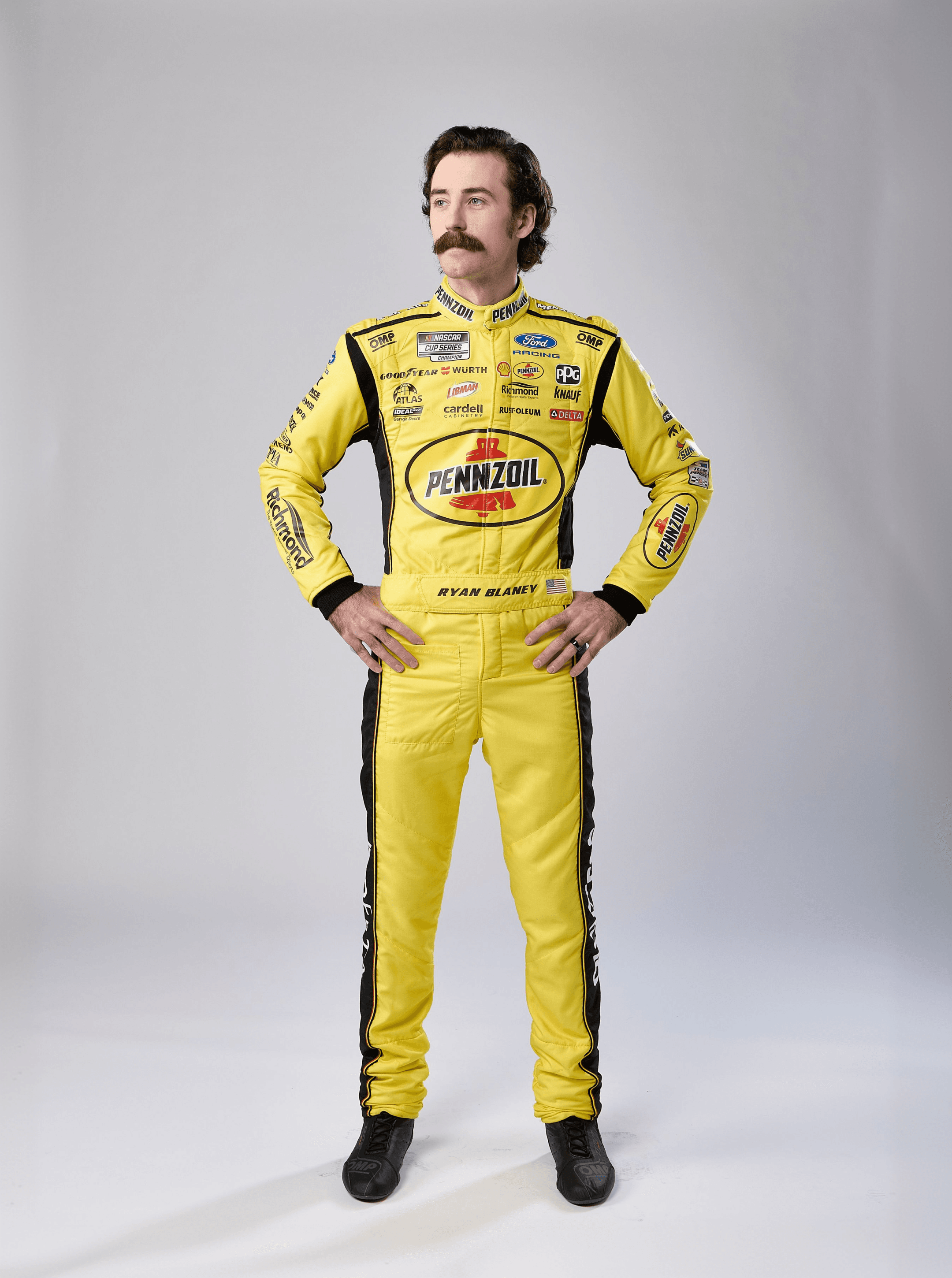 Mustached driver stands hands on hips in a yellow Pennzoil suit lined with black stripes