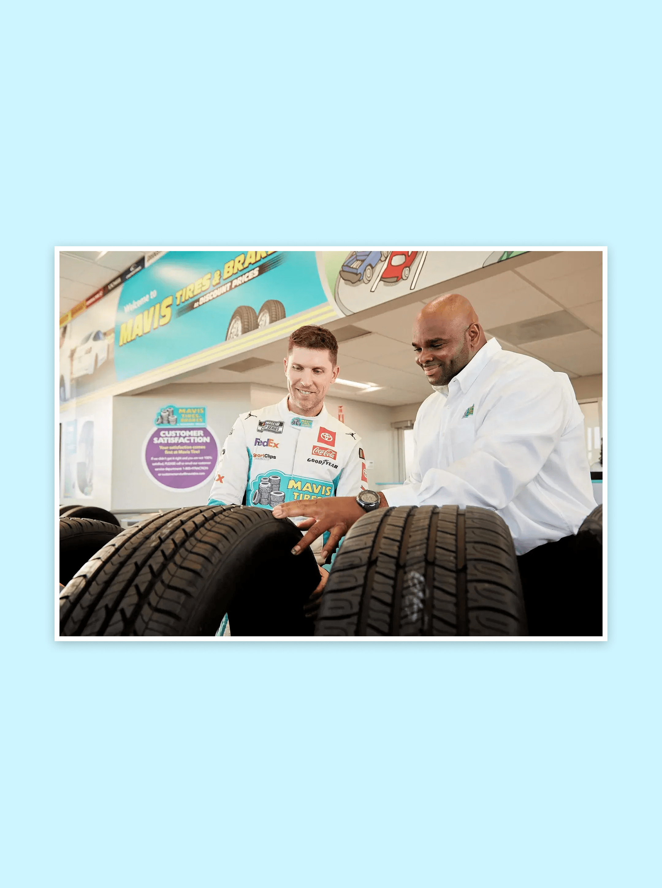 Driver in a Mavis Tires & Brakes fire suit and a store employee inspecting tires under the welcome banner