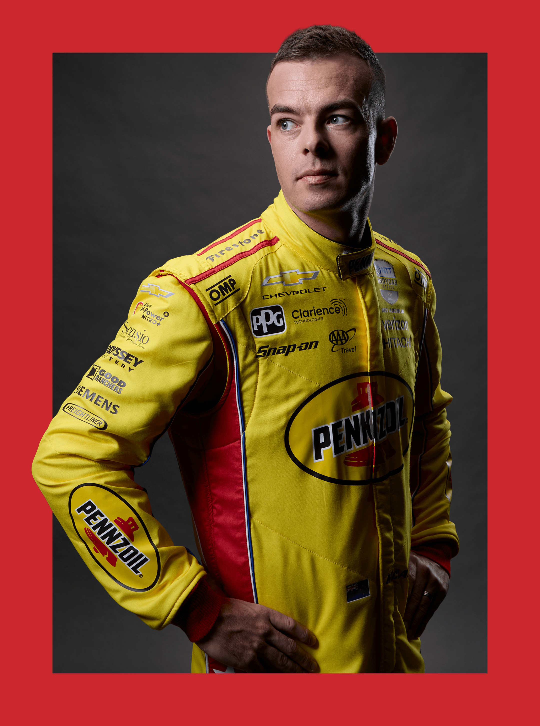 Waist-up portrait of a driver in a yellow Pennzoil suit crowded with sponsor patches on dark grey