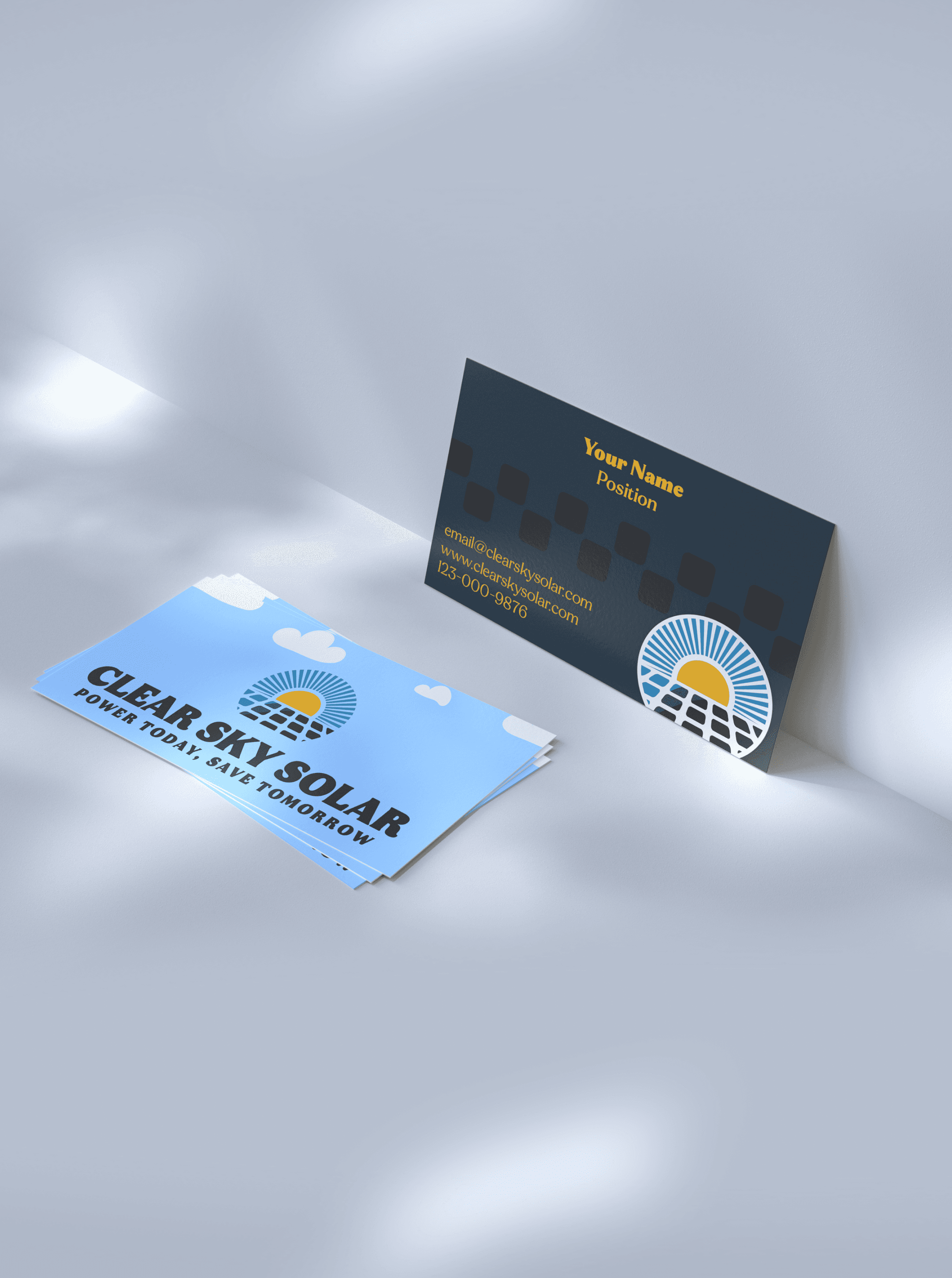 Clear Sky Solar business cards in a grey studio setup, a sky blue front stack beside a navy back with contact lines