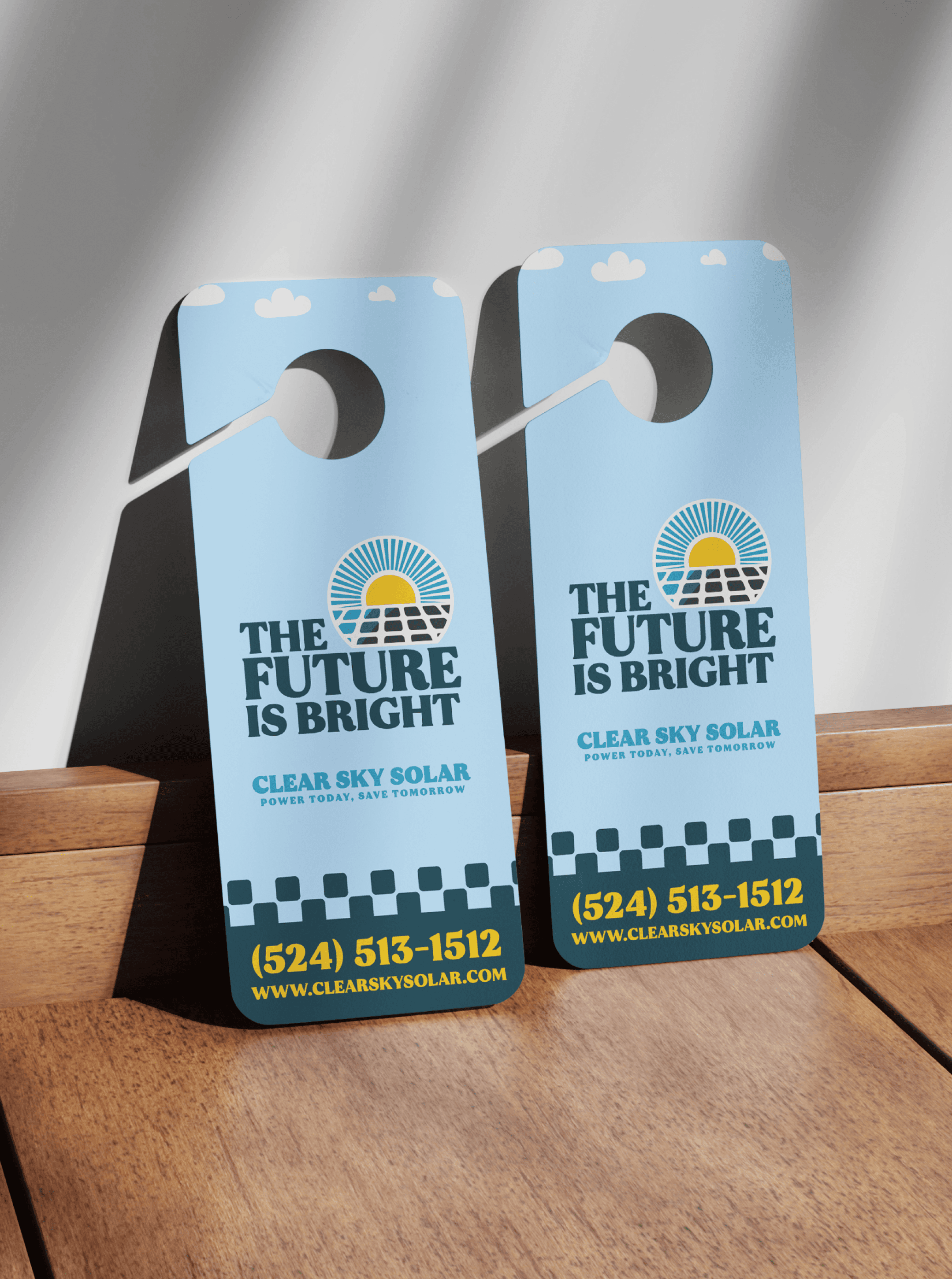 Two Clear Sky Solar door hangers on a wood surface reading "THE FUTURE IS BRIGHT" with the number (524) 513-1512