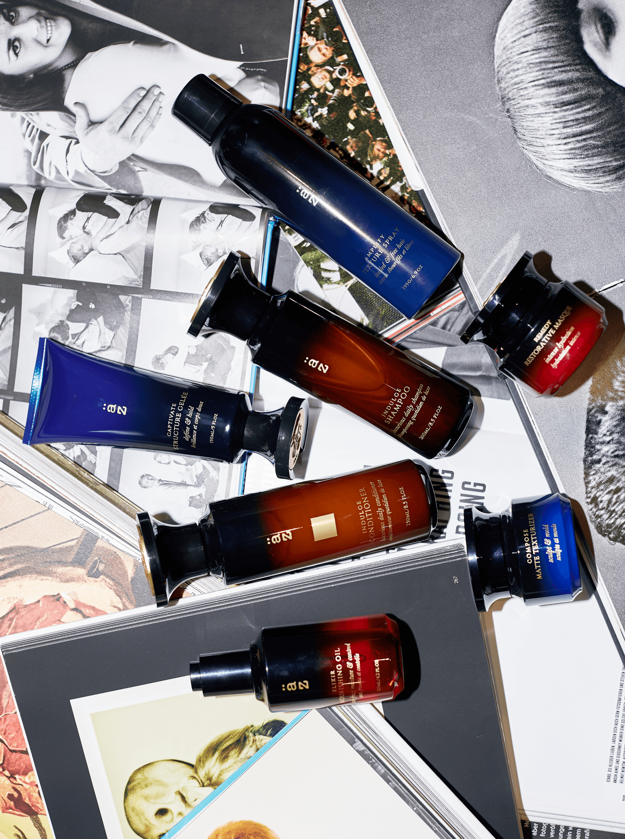 Six AZ bottles in navy, amber and red fanned across open magazines and photo prints, shot from above
